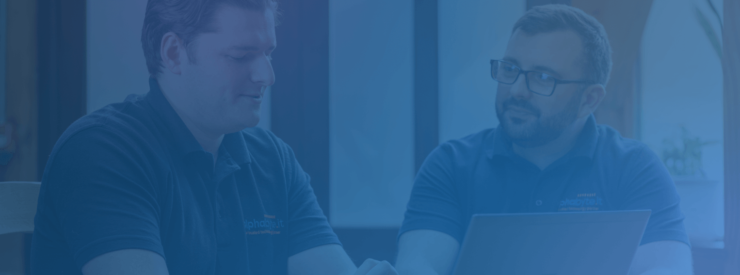 Two members of the Alphabyte IT team talking at a laptop