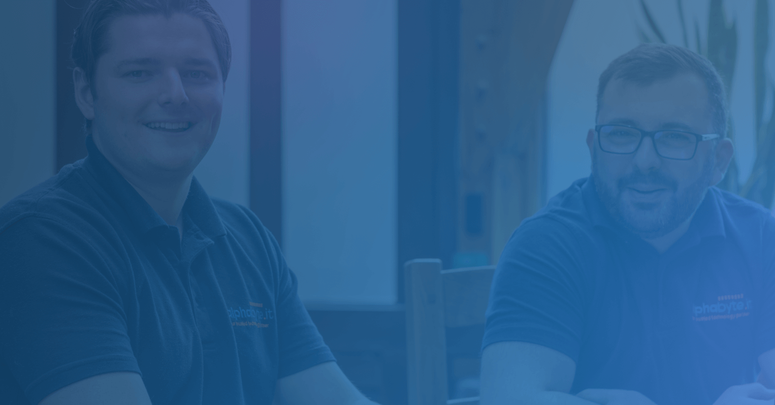 Two members of the Alphabyte IT team smiling at a desk